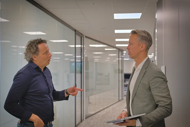 Twee collega's in gesprek op een kantoorgang